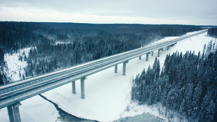 空中实拍白雪皑皑的森林中行驶在桥上的汽车