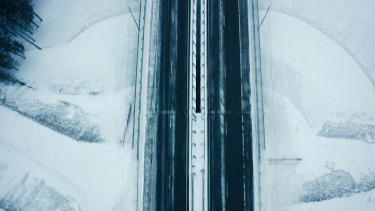在白雪皑皑的丛林空中的高速公路上行驶的汽车